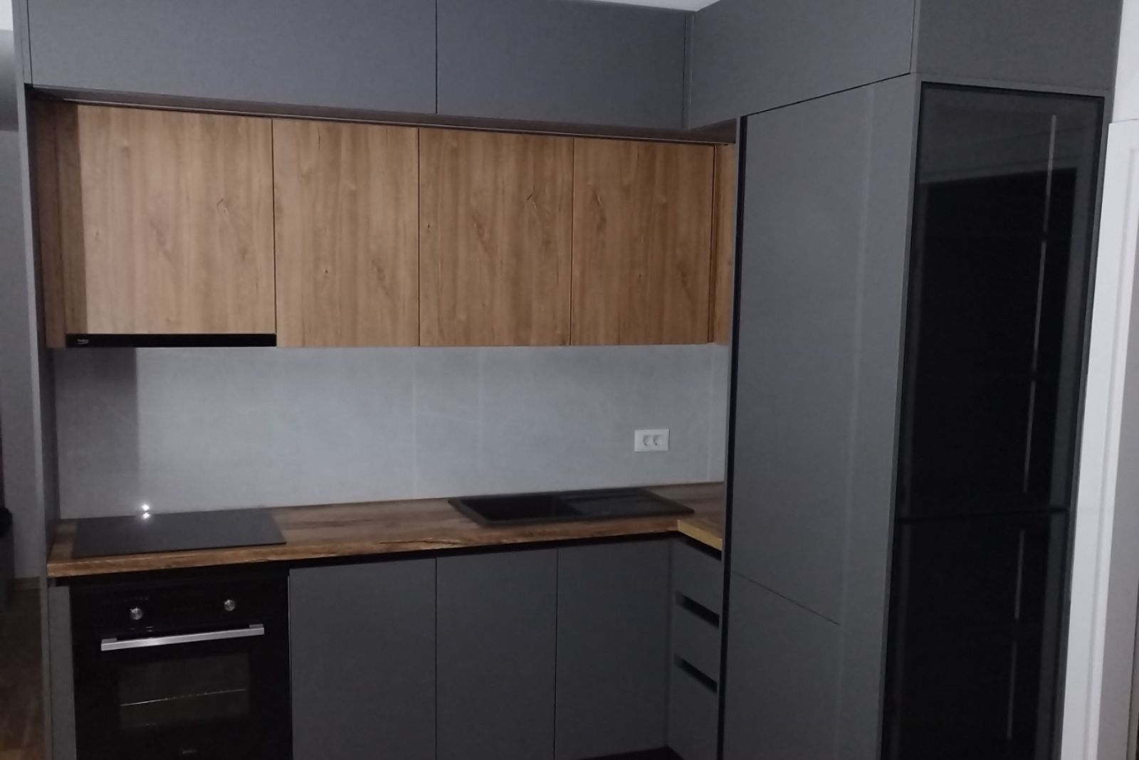 tamno siva kuhinja u kombinaciji sa drvenim dezenom, do plafona i ugadnim kuhinjskim elementima